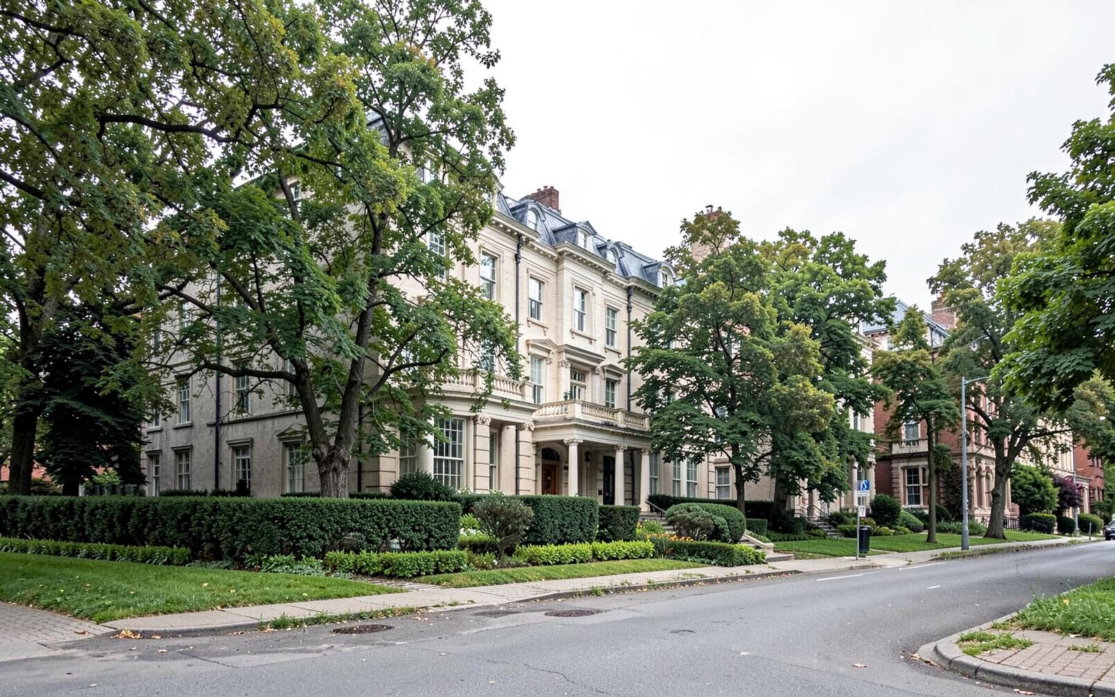Quiet upscale street with stately homes behind mature trees
